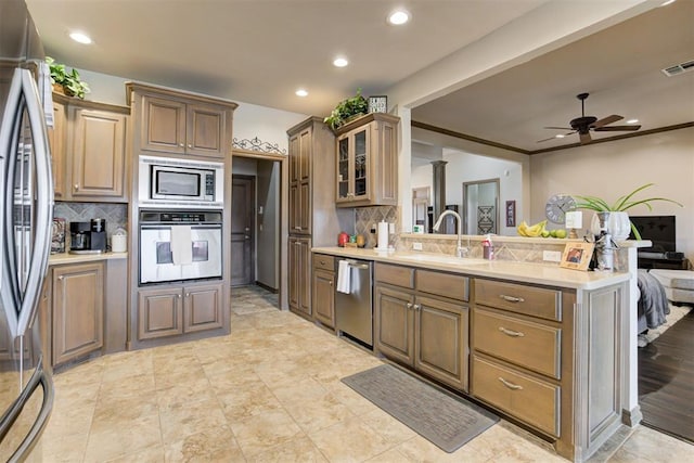 kitchen featuring a sink, a peninsula, tasteful backsplash, and stainless steel appliances