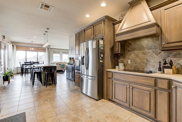 kitchen with premium range hood, recessed lighting, backsplash, stainless steel refrigerator with ice dispenser, and visible vents