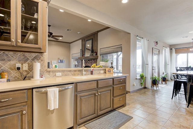 kitchen featuring decorative backsplash, ceiling fan, stainless steel dishwasher, a fireplace, and a sink