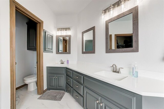 full bath with double vanity, toilet, a sink, and marble finish floor