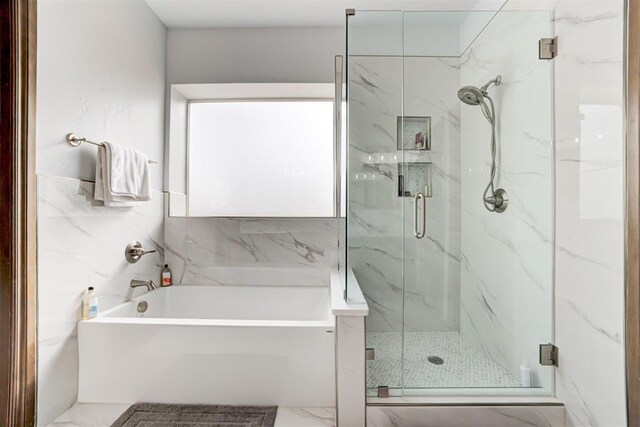 bathroom featuring tile walls, a marble finish shower, marble finish floor, and a garden tub