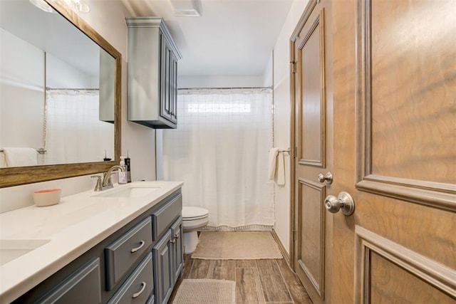 bathroom with double vanity, visible vents, wood finished floors, a sink, and toilet
