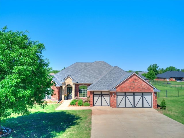view of front of home featuring fence, an attached garage, brick siding, and a front yard