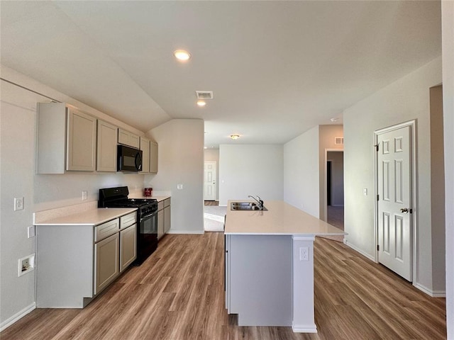 kitchen featuring sink, black appliances, a center island with sink, gray cabinets, and lofted ceiling