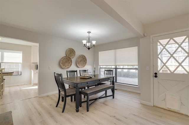 dining room with beamed ceiling, a wealth of natural light, a notable chandelier, and light hardwood / wood-style flooring