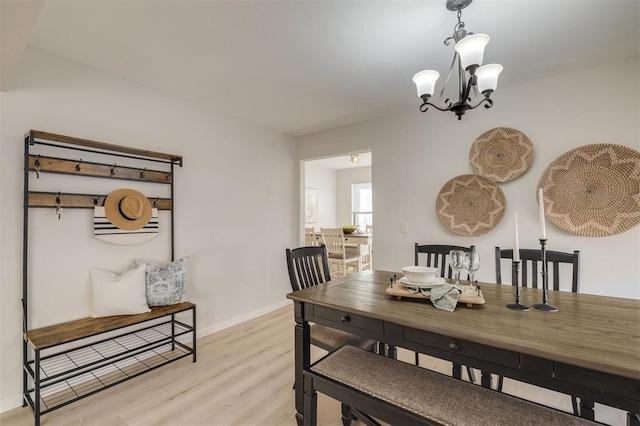 dining space featuring light wood-type flooring and a notable chandelier