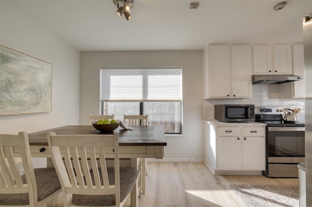 kitchen with stainless steel appliances, light hardwood / wood-style flooring, decorative backsplash, and white cabinetry