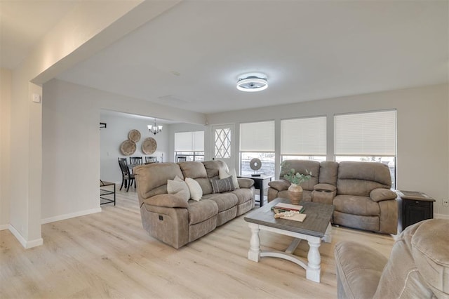 living room featuring light hardwood / wood-style flooring, an inviting chandelier, and a wealth of natural light