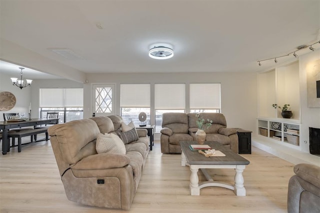 living room with light hardwood / wood-style floors and a notable chandelier