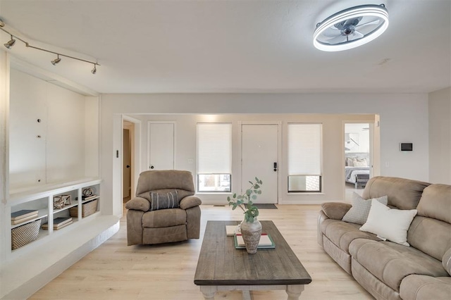 living room featuring rail lighting, ceiling fan, and light hardwood / wood-style flooring