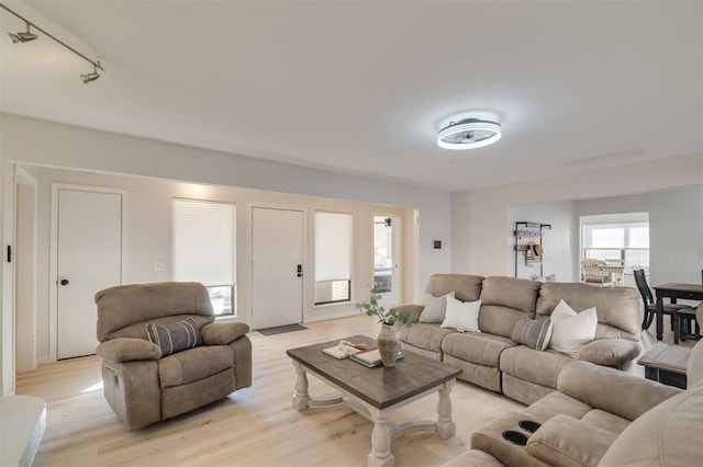 living room with rail lighting and light hardwood / wood-style flooring