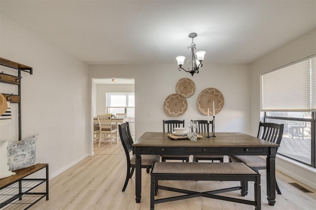 dining area with light hardwood / wood-style flooring and a chandelier