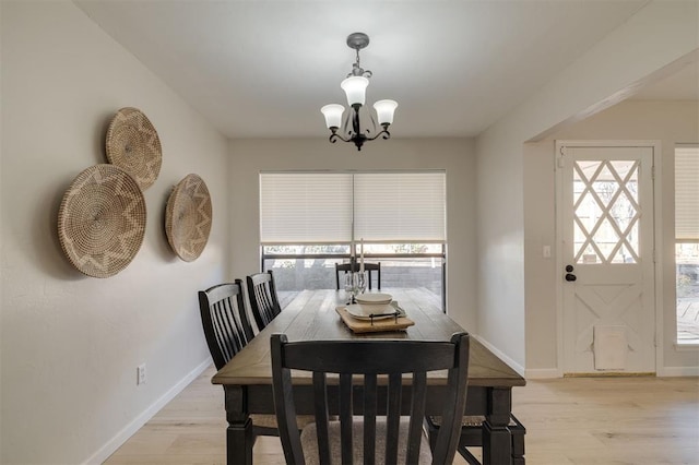 dining room with a healthy amount of sunlight, a notable chandelier, and light hardwood / wood-style floors