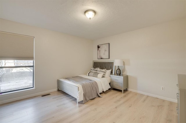 bedroom featuring a textured ceiling and light hardwood / wood-style floors