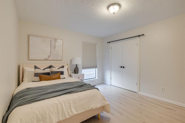 bedroom featuring a textured ceiling, a closet, and light hardwood / wood-style flooring