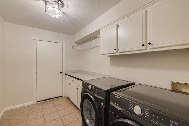 washroom with cabinets, washing machine and clothes dryer, and light tile patterned floors