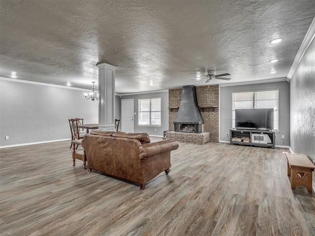 living room featuring a wood stove, ceiling fan with notable chandelier, crown molding, hardwood / wood-style flooring, and a textured ceiling