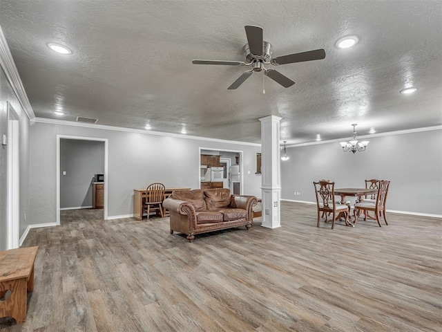 living room featuring decorative columns, wood-type flooring, a textured ceiling, ceiling fan with notable chandelier, and ornamental molding