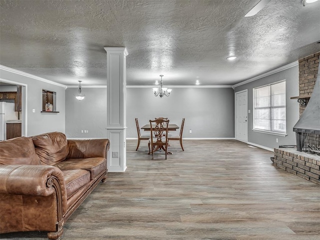 living room featuring decorative columns, crown molding, light hardwood / wood-style floors, and a textured ceiling