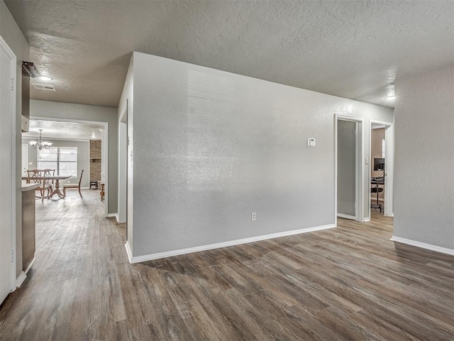 spare room featuring wood-type flooring, a textured ceiling, and a chandelier