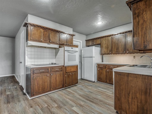 kitchen featuring a textured ceiling, tasteful backsplash, sink, and white appliances