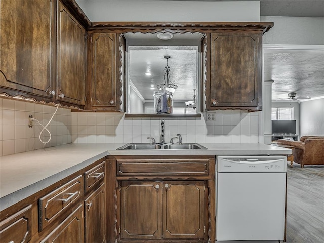 kitchen featuring white dishwasher, backsplash, dark brown cabinetry, and sink