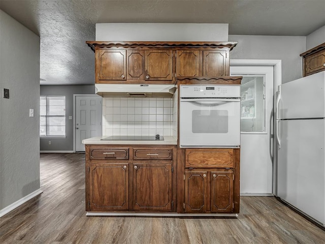 kitchen featuring tasteful backsplash, white appliances, and hardwood / wood-style flooring