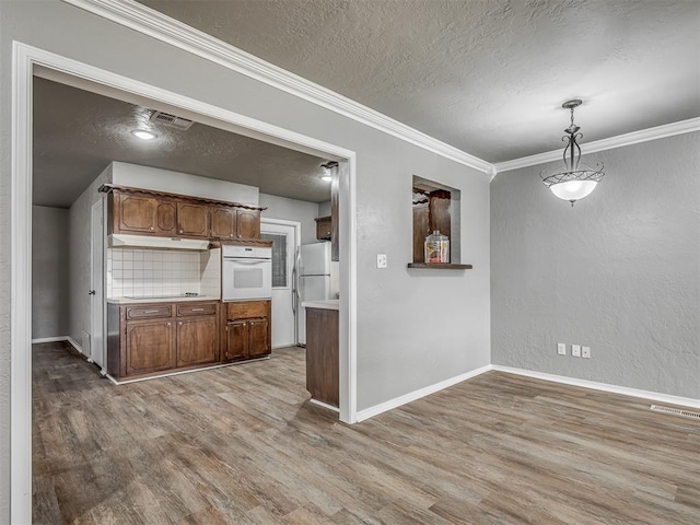 kitchen featuring a textured ceiling, white appliances, tasteful backsplash, and hanging light fixtures