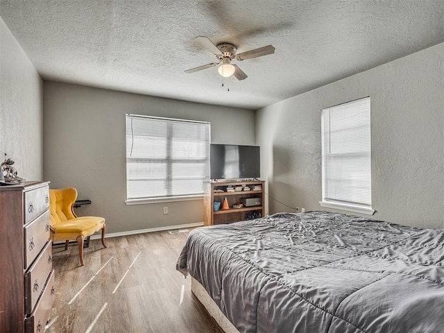 bedroom featuring multiple windows, ceiling fan, light hardwood / wood-style flooring, and a textured ceiling