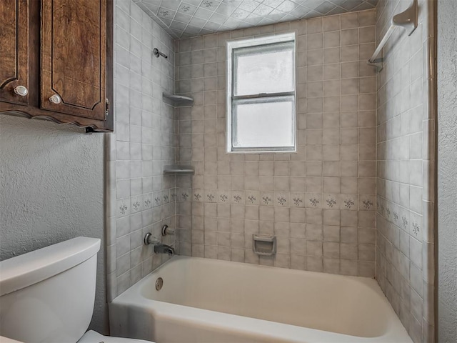 bathroom with toilet and tiled shower / bath