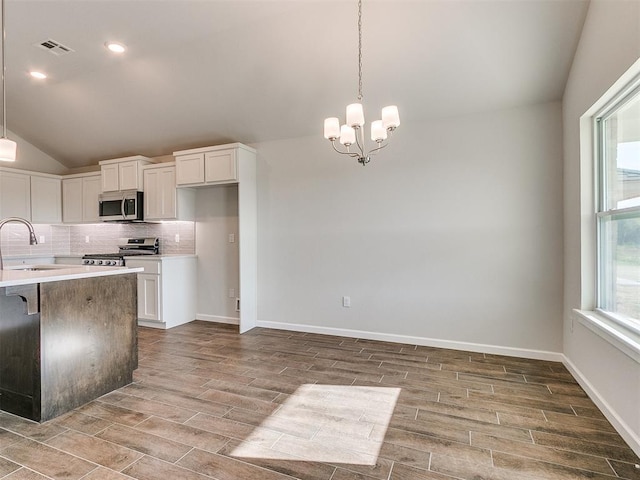 kitchen with stove, a chandelier, white cabinetry, hanging light fixtures, and lofted ceiling