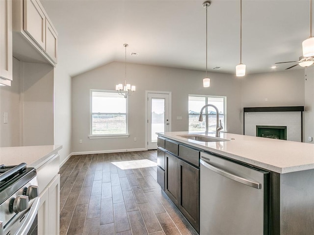 kitchen with ceiling fan with notable chandelier, stainless steel appliances, a kitchen island with sink, sink, and hanging light fixtures