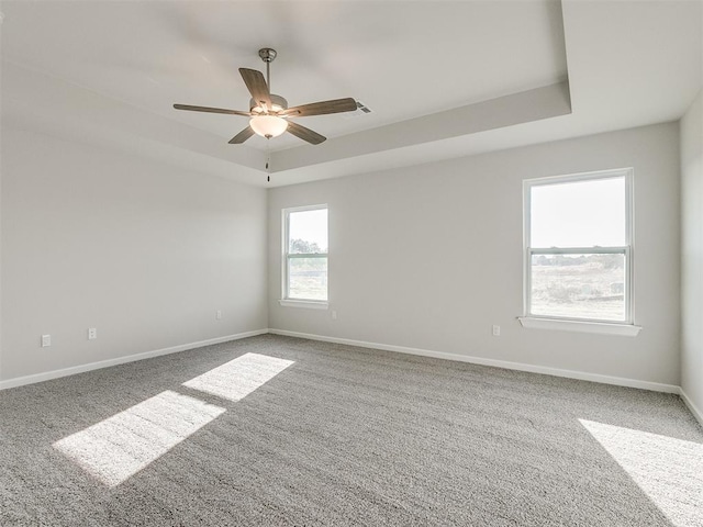 carpeted empty room with a raised ceiling and ceiling fan