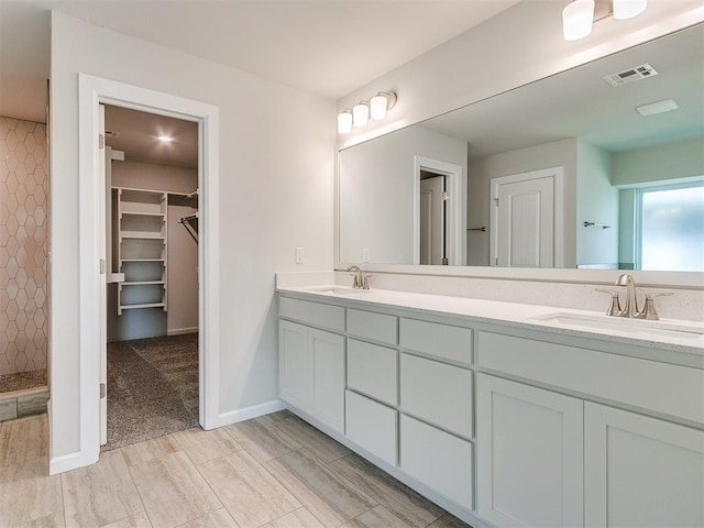 bathroom featuring tiled shower and vanity