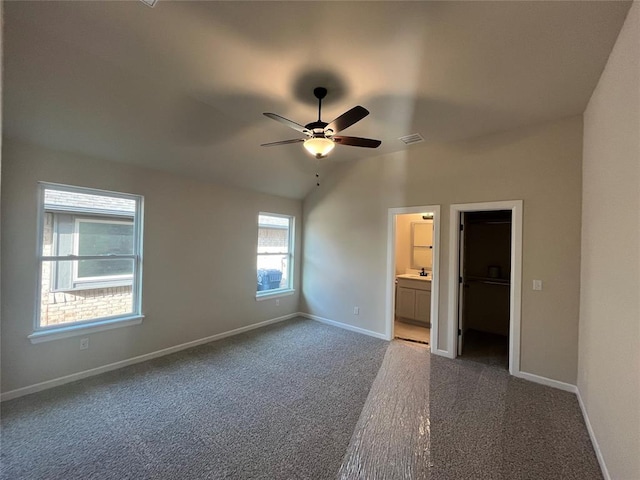 unfurnished bedroom with ceiling fan, ensuite bathroom, lofted ceiling, a walk in closet, and a closet