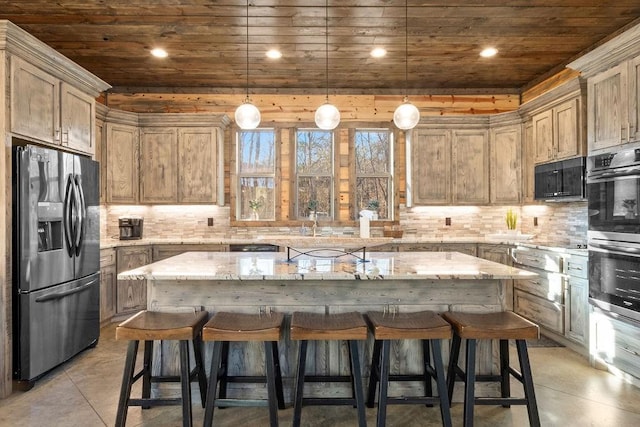 kitchen featuring decorative light fixtures, light stone countertops, stainless steel appliances, and a center island