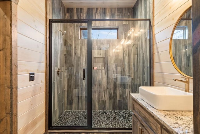 bathroom featuring an enclosed shower, vanity, and wooden walls