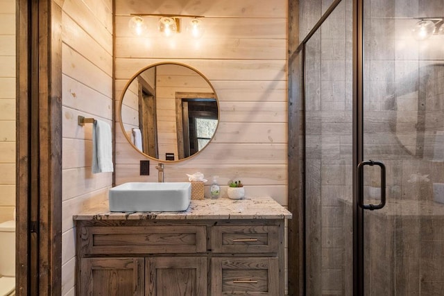 bathroom with a shower with shower door, toilet, vanity, and wood walls