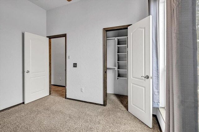 unfurnished bedroom featuring light carpet, a walk in closet, and a closet