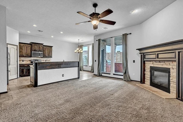 unfurnished living room featuring ceiling fan with notable chandelier, a stone fireplace, light carpet, and a textured ceiling