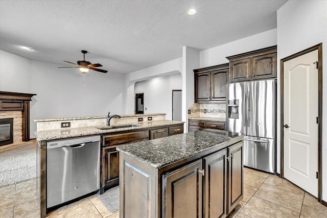 kitchen with sink, stainless steel appliances, a center island, and stone countertops