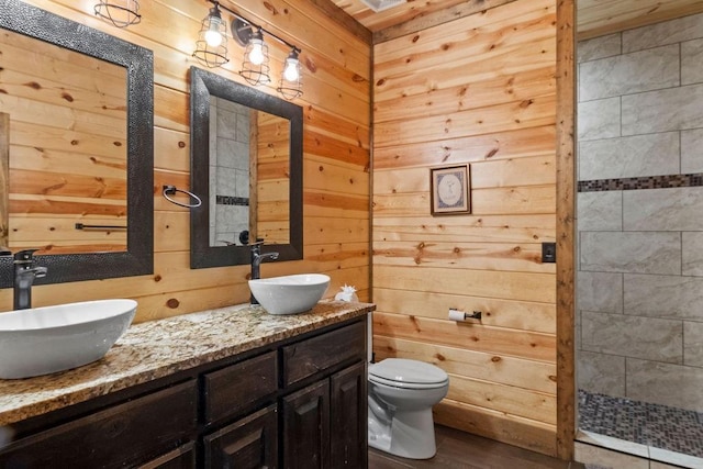 bathroom featuring vanity, toilet, a shower, and wooden walls