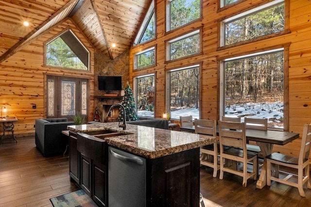 kitchen featuring wood ceiling, a center island with sink, wooden walls, dishwasher, and high vaulted ceiling