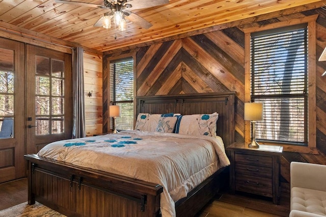 bedroom with ceiling fan, wood-type flooring, wood ceiling, and wooden walls