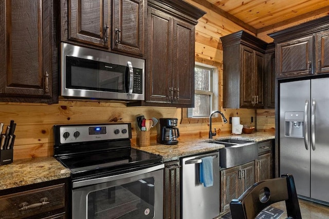 kitchen with appliances with stainless steel finishes, sink, wood walls, wooden ceiling, and dark brown cabinets