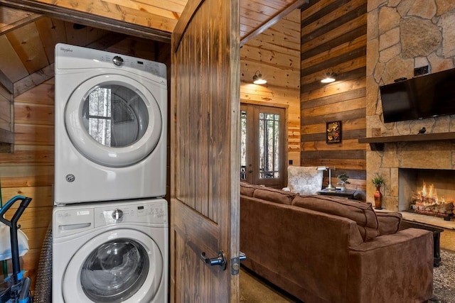 clothes washing area with wood walls, stacked washer and dryer, and a fireplace