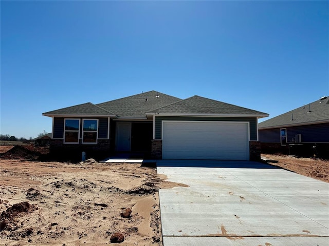 view of front facade with a garage, driveway, and a shingled roof