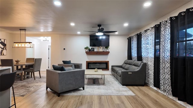 living room with light hardwood / wood-style floors and ceiling fan with notable chandelier