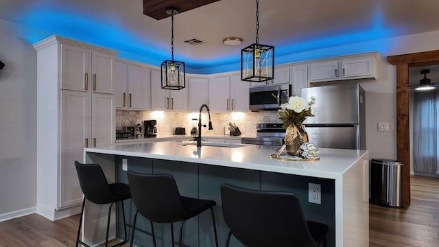 kitchen with hanging light fixtures, white cabinets, sink, and stainless steel appliances