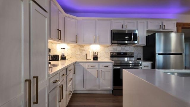 kitchen featuring white cabinets, decorative backsplash, dark wood-type flooring, and stainless steel appliances